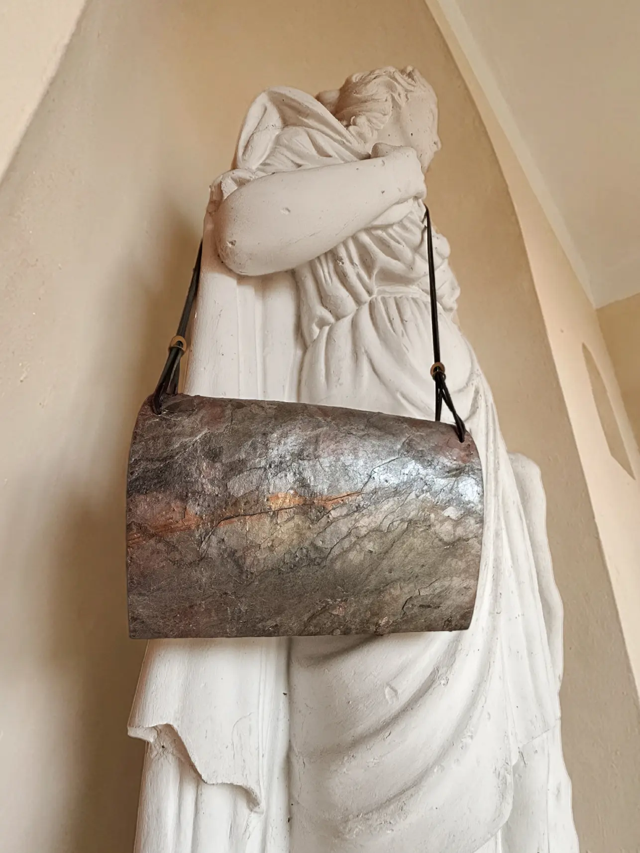 Pyroklast Abendtasche von einer weißen Statue getragen